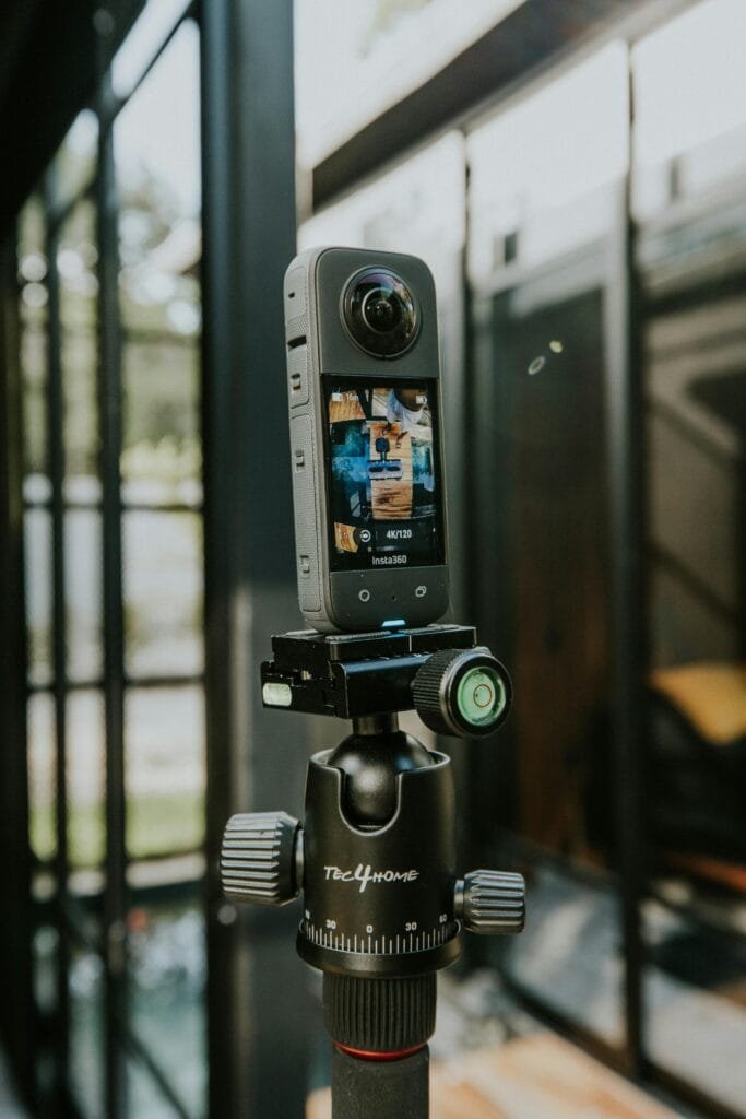 A 360-degree camera mounted on a tripod outdoors in a modern styled location.